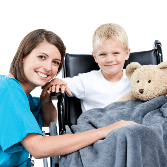 A caregiver smiling beside a young boy with a teddy bear